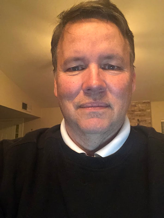 image of Gary VG wearing a black sweater over a white shirt in an indoor setting